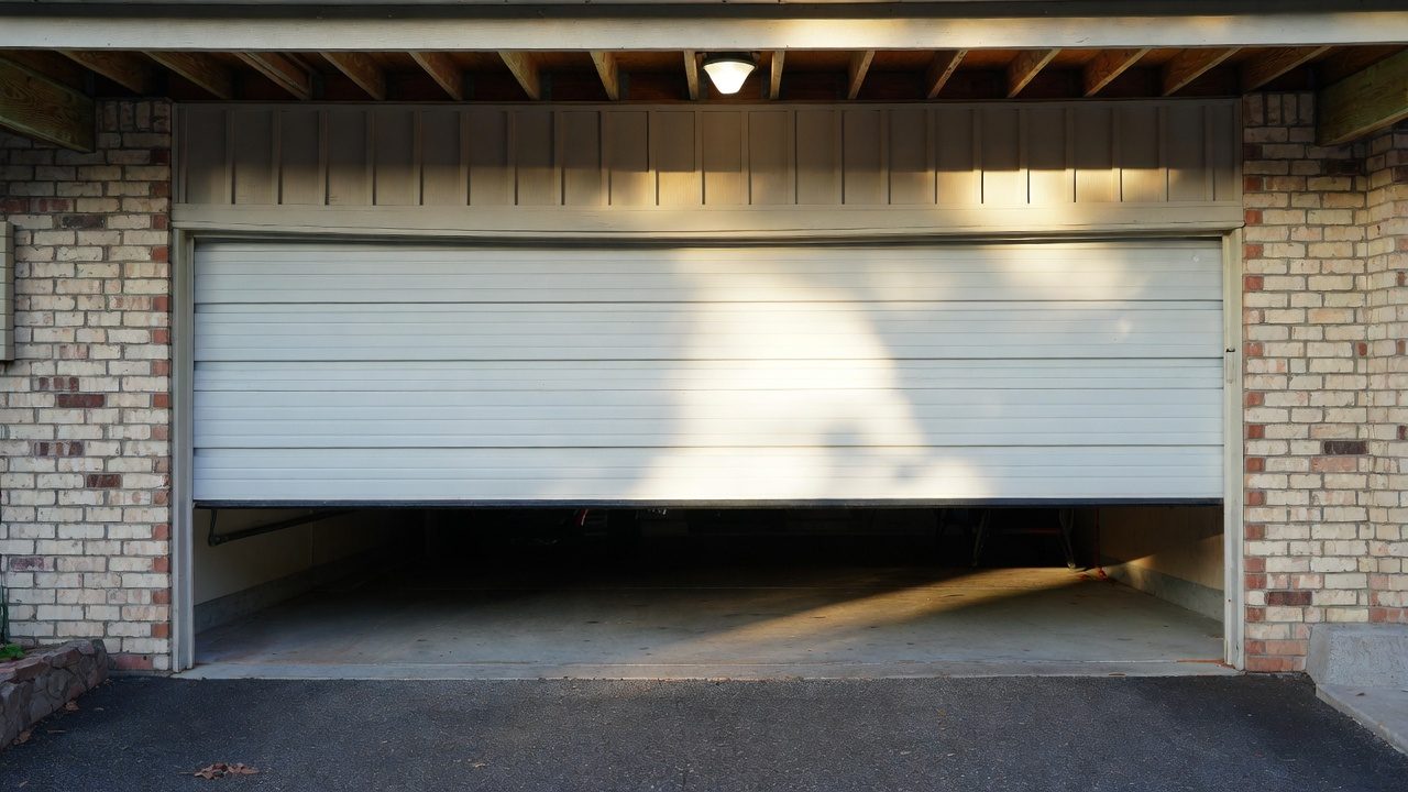 Garage door stuck halfway open on a brick home — common repair issue in North Alabama